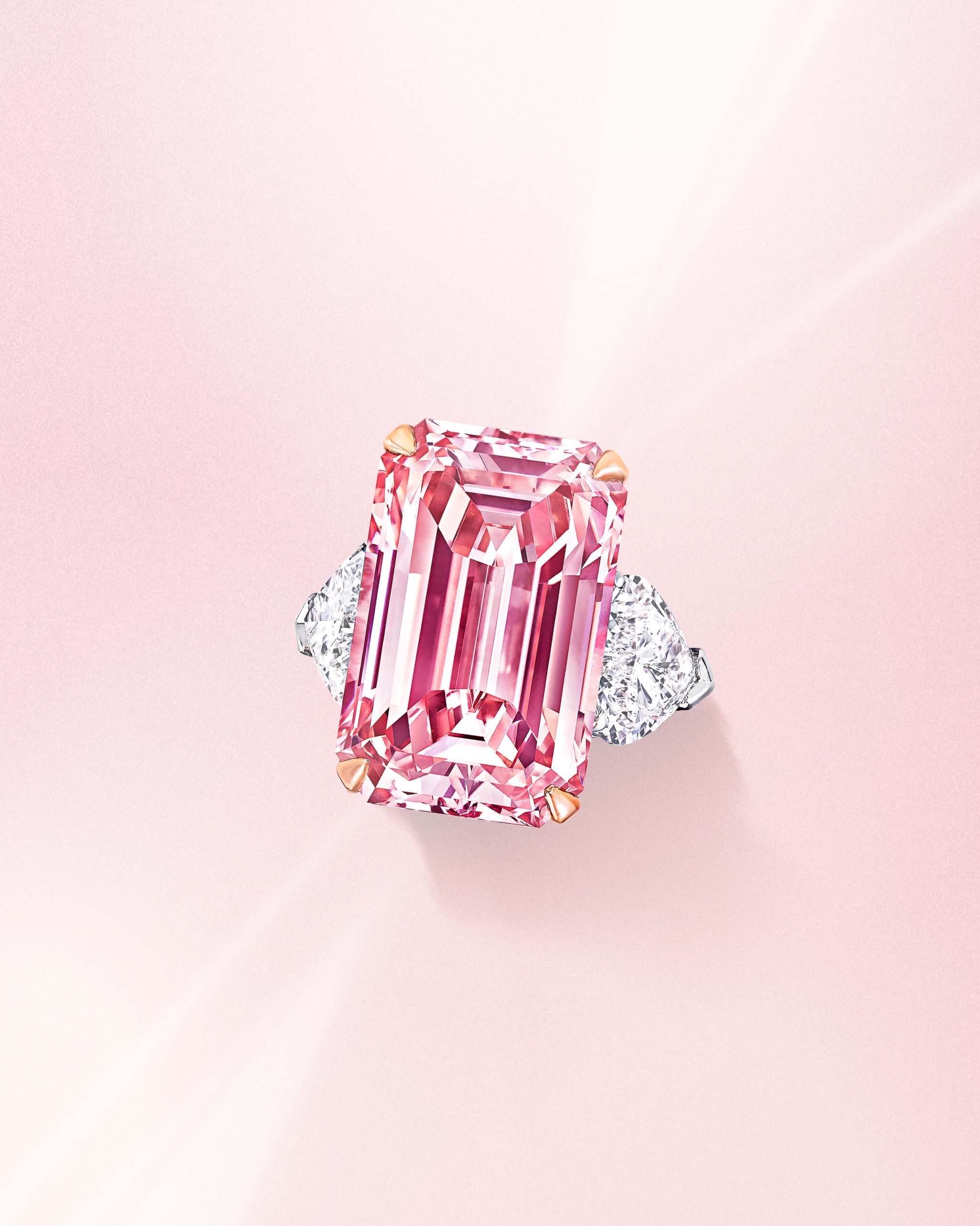 Rectangular emerald cut pink diamond ring with side white diamonds on a platinum band from Graff